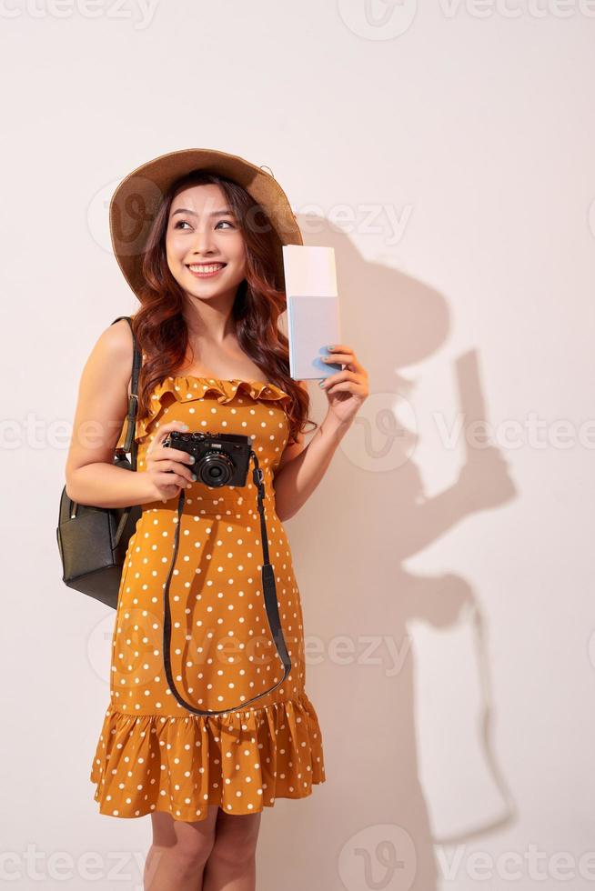 femme touristique expressive en vêtements décontractés d'été, chapeau tenant un passeport, billets isolés sur fond beige. femme voyageant à l'étranger pour voyager le week-end. concept de voyage en avion photo