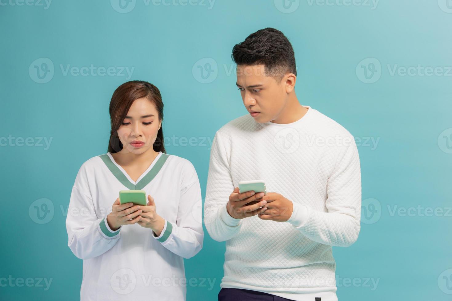 un jeune homme et une femme tapent sur leur téléphone portable. l'homme regarde le téléphone de sa petite amie photo