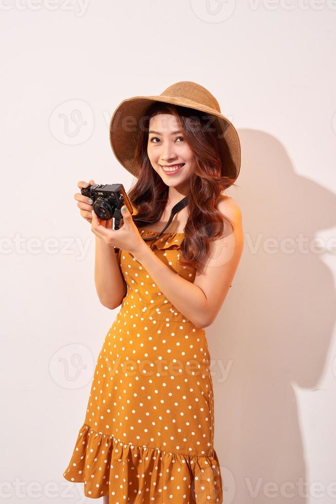 image d'une jeune femme photographe isolée sur un mur de fond beige tenant l'appareil photo. photo