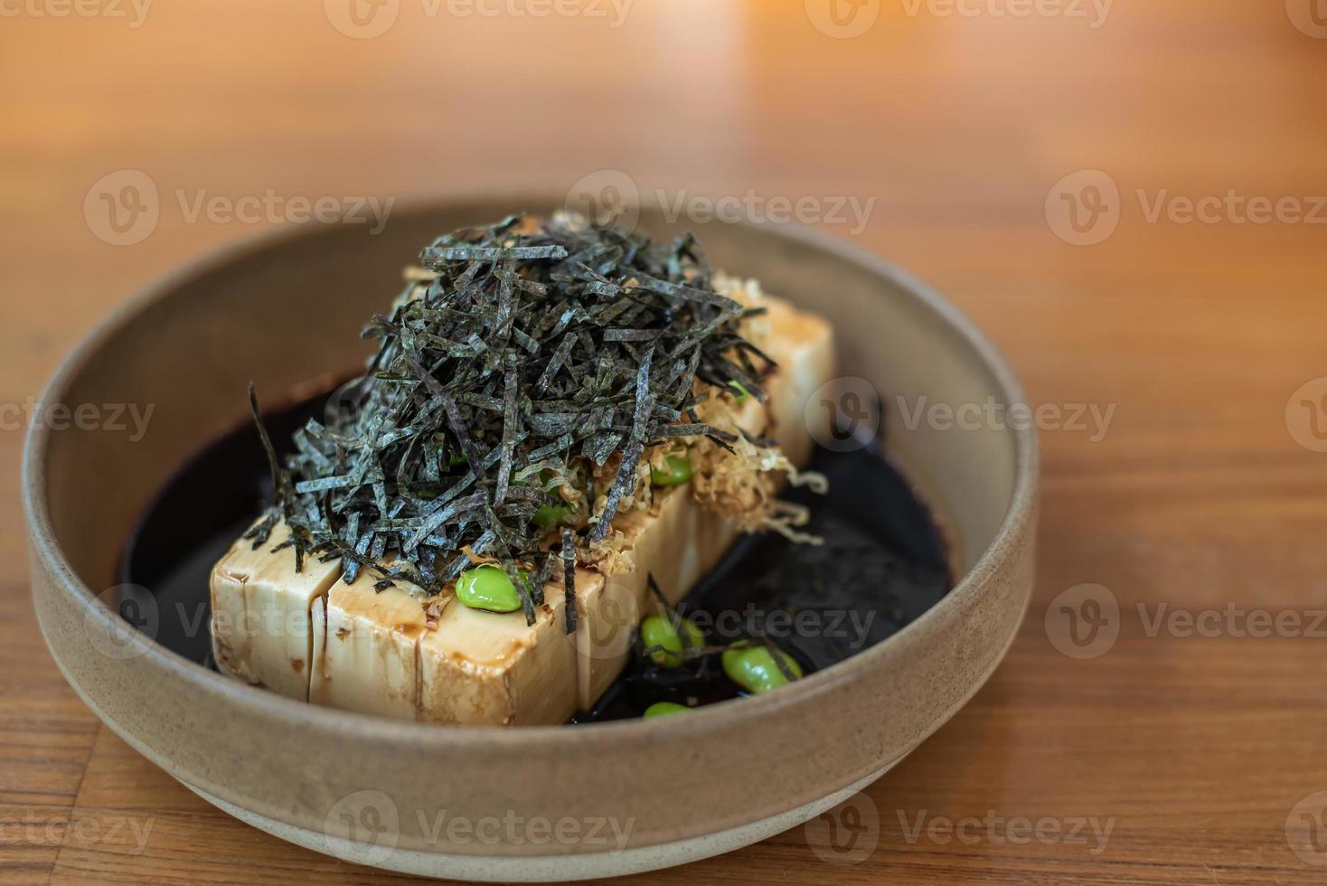 gros plan de tofu froid avec sauce soja dashi, garniture d'algues et edamame dans un bol en faïence de style japonais. photo