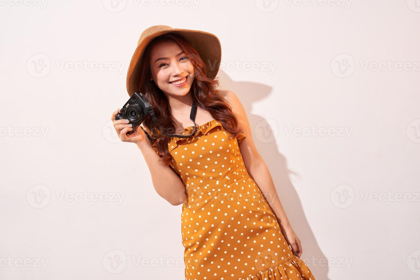 image d'une jeune femme photographe isolée sur un mur de fond beige tenant l'appareil photo. photo