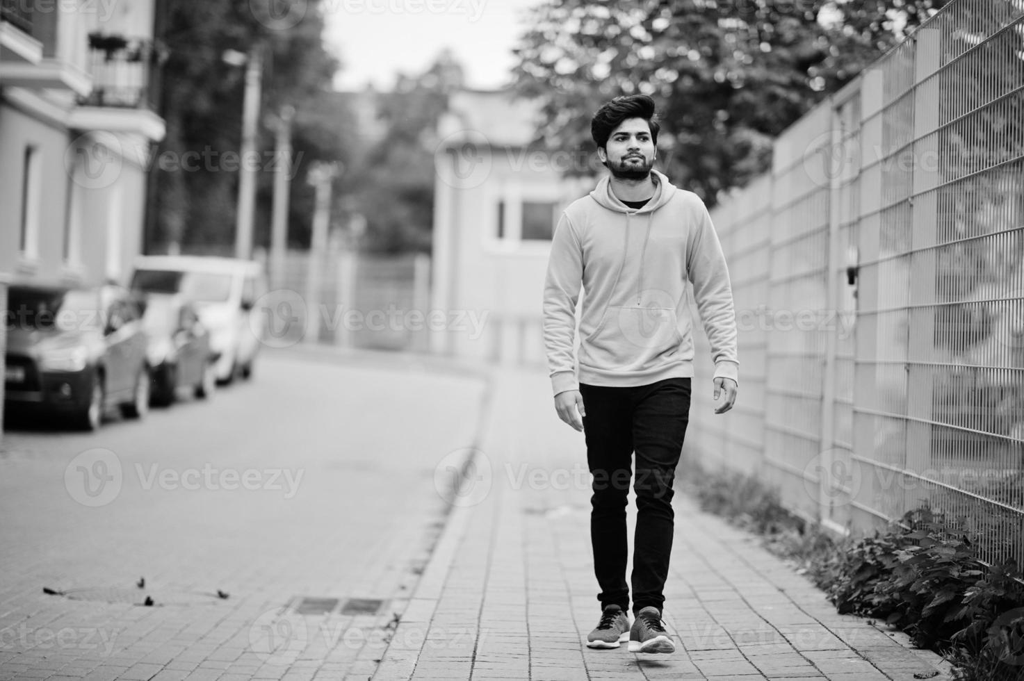 jeune homme indien hipster urbain dans un sweat-shirt jaune à la mode. un mec sud-asiatique cool porte un sweat à capuche marchant dans la rue d'automne. photo