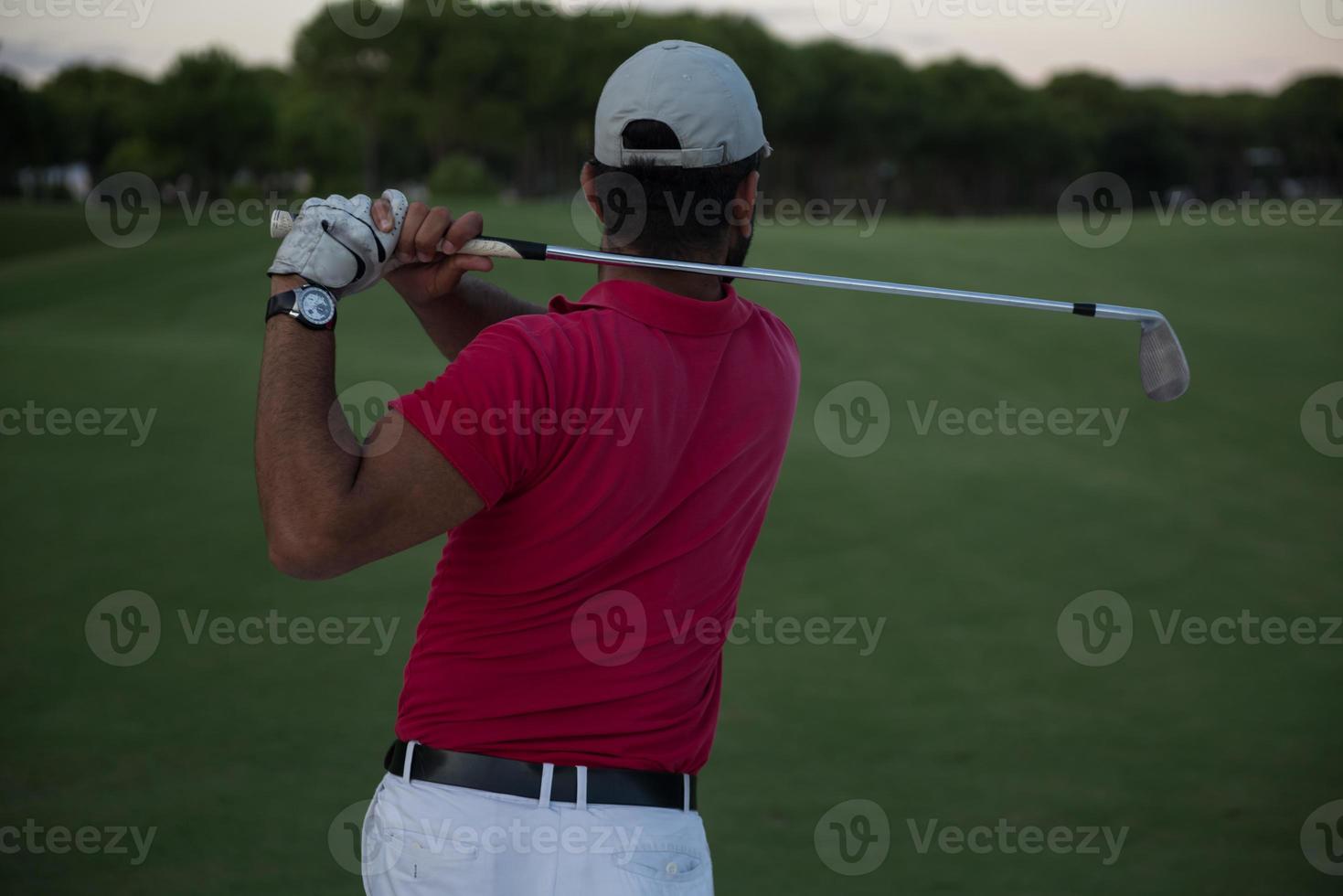 golfeur frappant un bunker de sable tourné au coucher du soleil photo