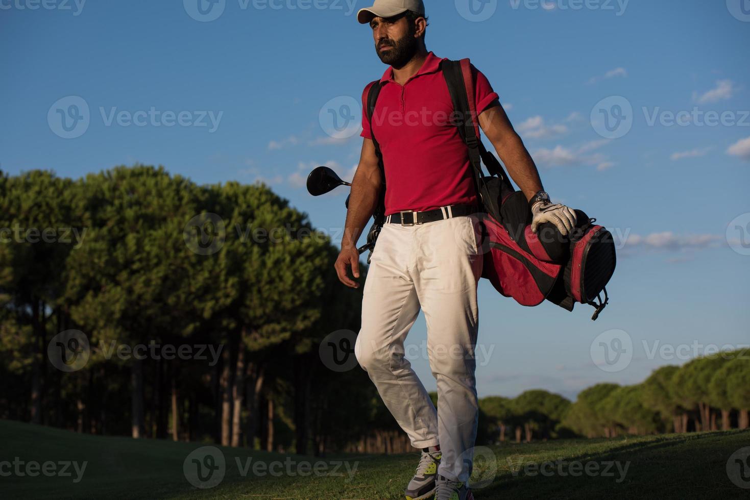 golfeur marchant et portant un sac de golf photo