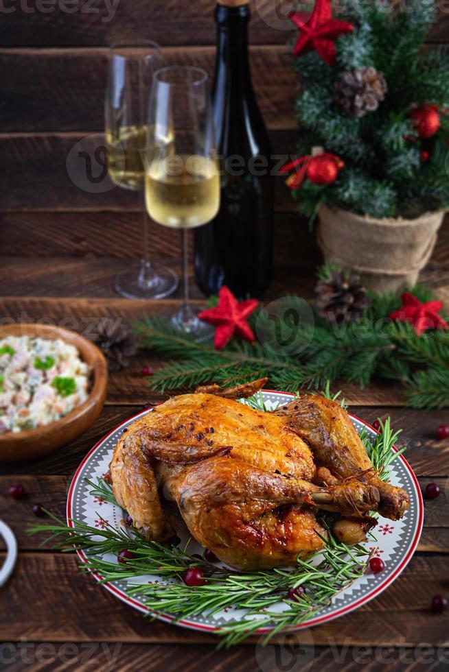 poulet entier ou dinde cuit au four pour noël. table du nouvel an avec décoration, poulet rôti maison, vin et salade photo