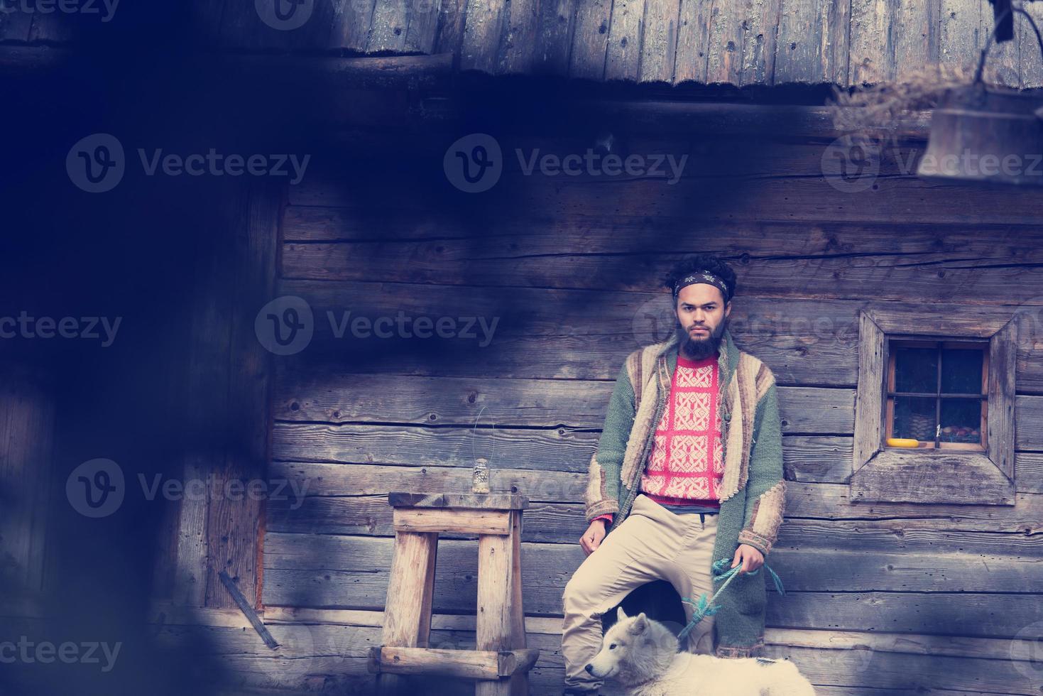 Hipster avec chien devant une maison en bois photo