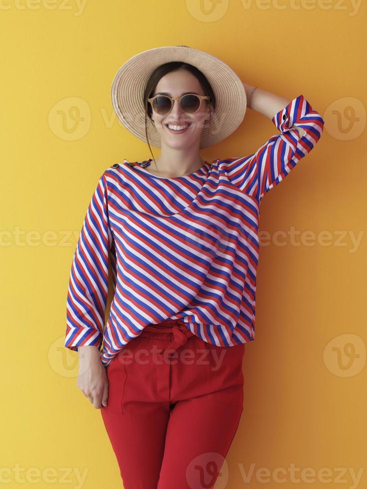 portrait de jeune femme portant des lunettes de soleil et un chapeau sur fond jaune photo