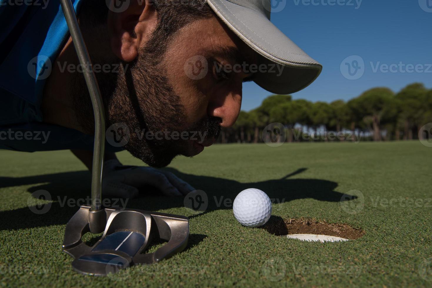 joueur de golf soufflant une balle dans le trou photo