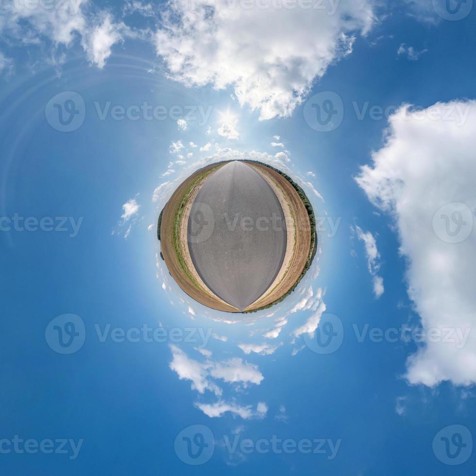 petite planète avec route dans le ciel bleu avec de beaux nuages. transformation du panorama sphérique à 360 degrés. vue aérienne abstraite sphérique. courbure de l'espace. photo