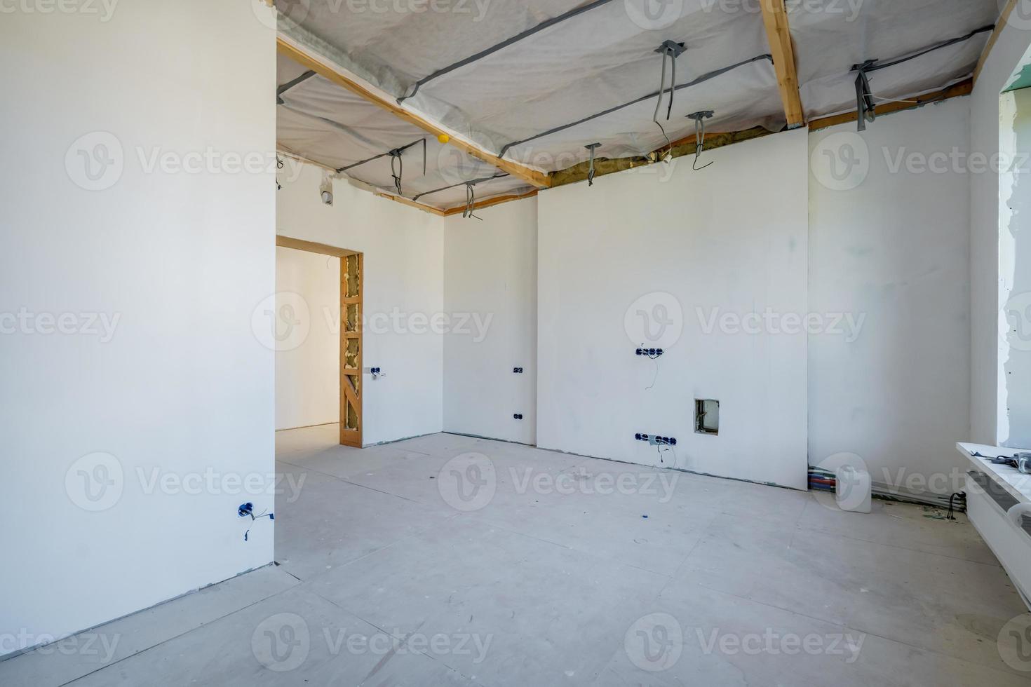 chambre vide non meublée avec un minimum de réparations préparatoires. intérieur avec murs blancs et cloisons sèches photo
