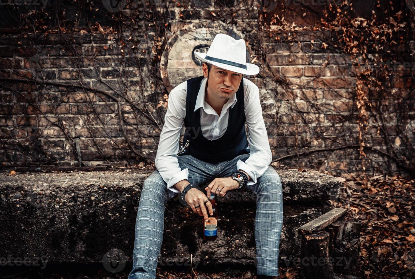 homme d'âge moyen avec un chapeau fedora se relaxant à l'extérieur et regardant la caméra. photo