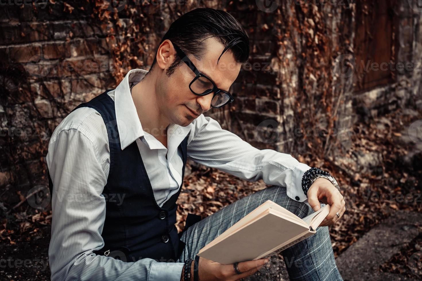 homme d'âge moyen souriant lisant un livre à l'extérieur. photo