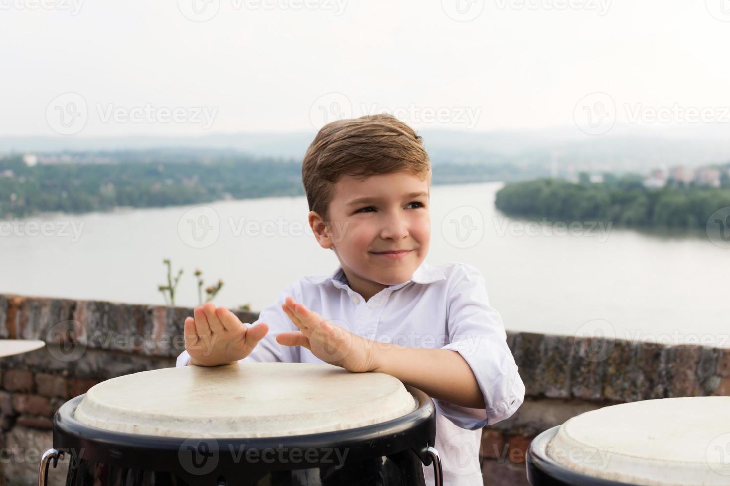 enfant souriant tapant sur les bongos. photo