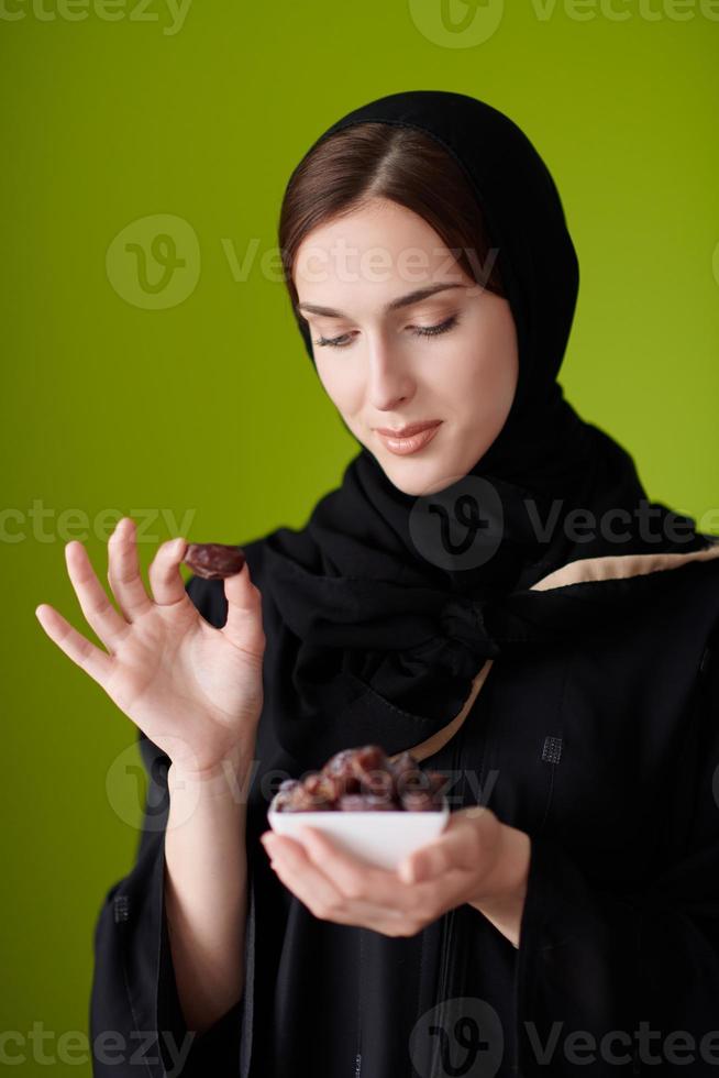 femme en abaya tenant une datte et un verre d'eau photo
