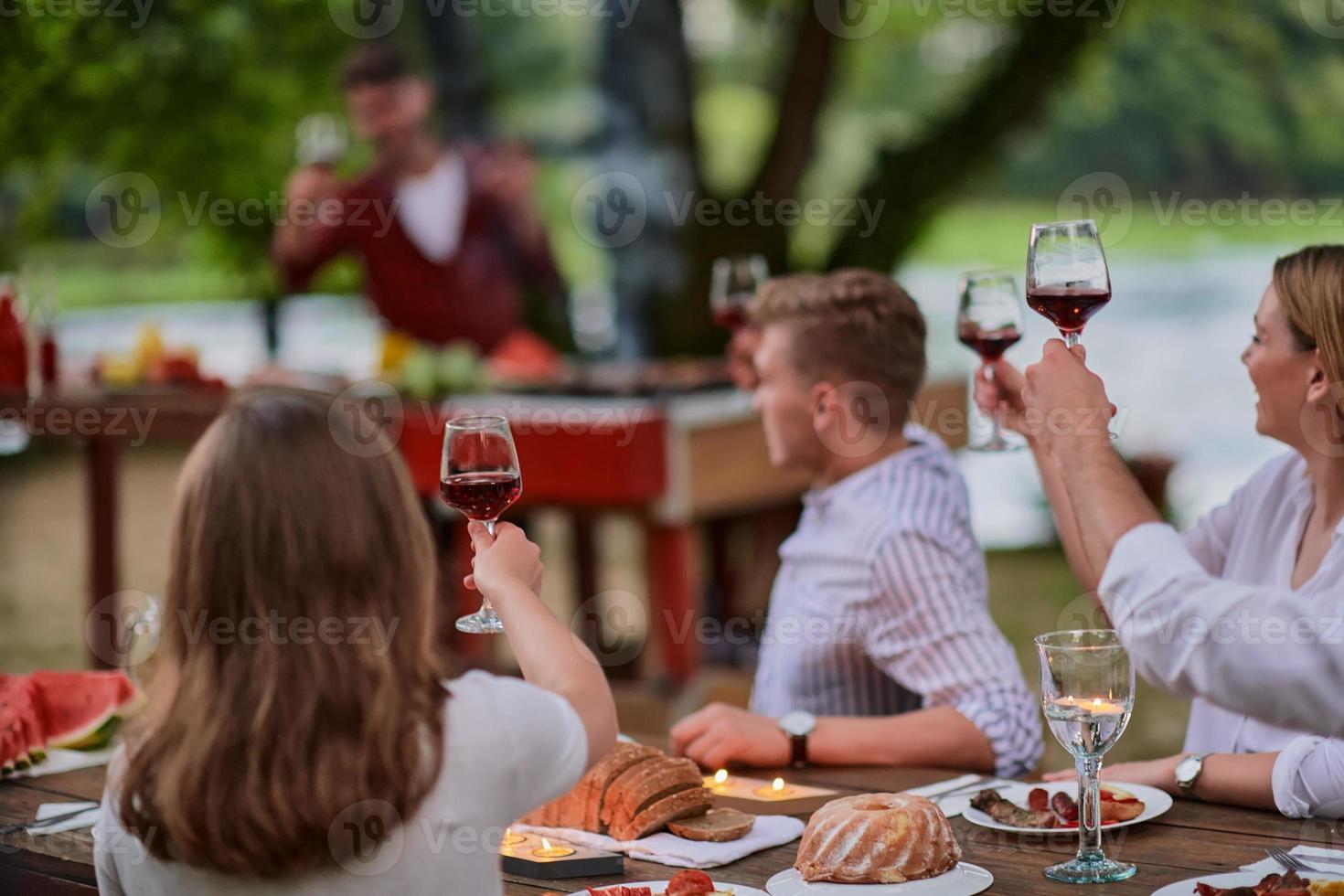 amis portant un verre de vin rouge tout en pique-nique dîner français en plein air photo