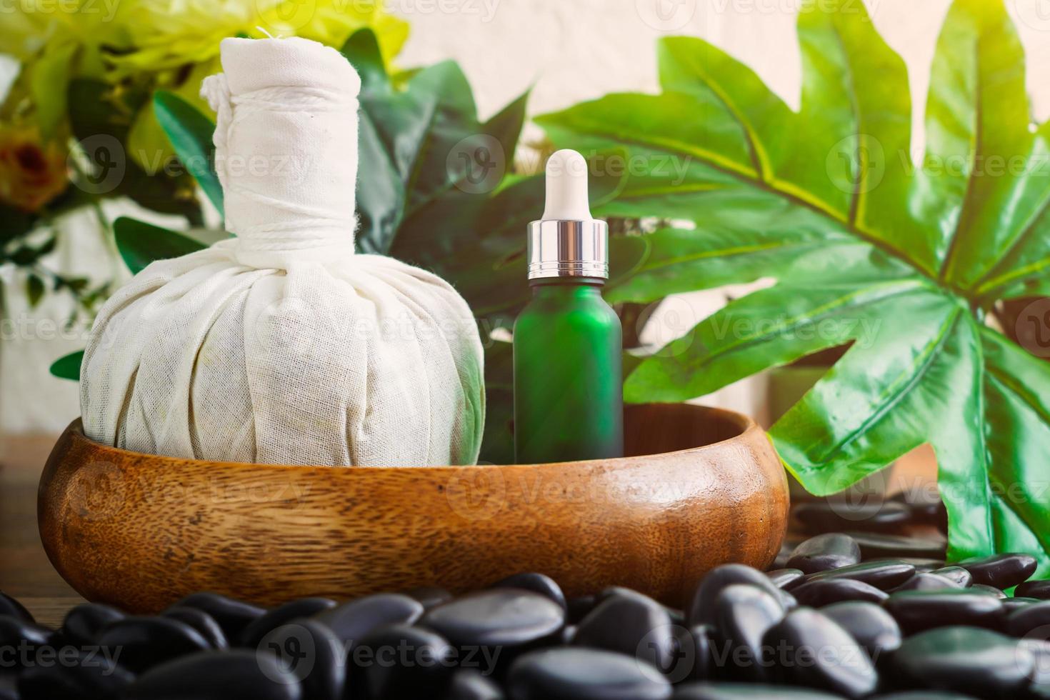 bouteille en verre cosmétique pour huiles essentielles et boules de compresse à base de plantes thaïlandaises sur pierre noire photo