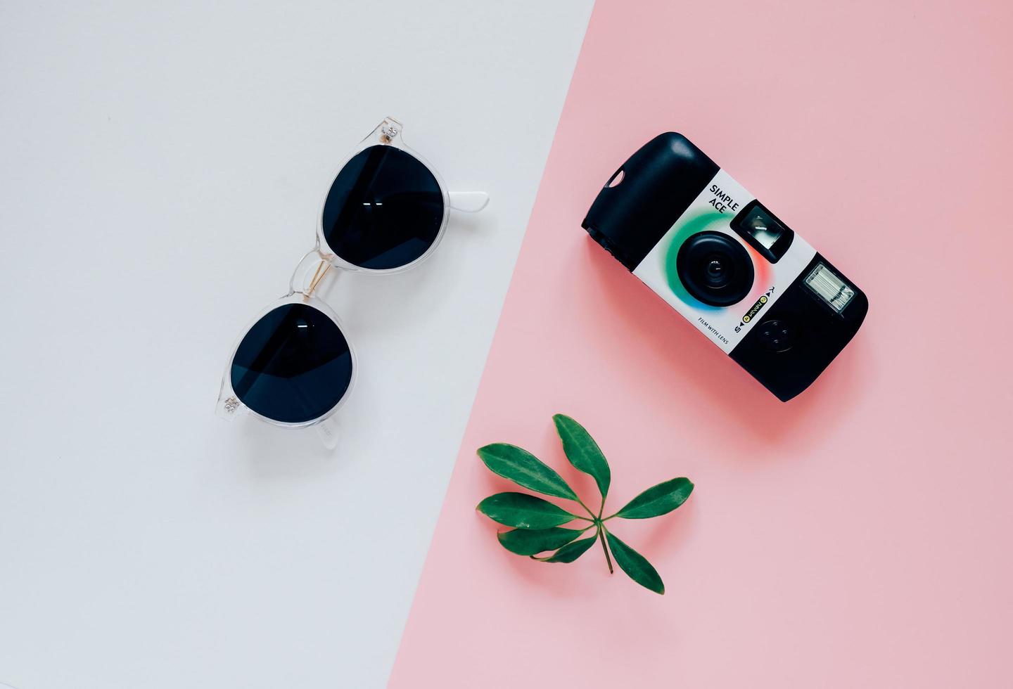 style plat créatif dans le concept de mode avec appareil photo et lunettes de soleil sur fond de couleur minimal, vue de dessus