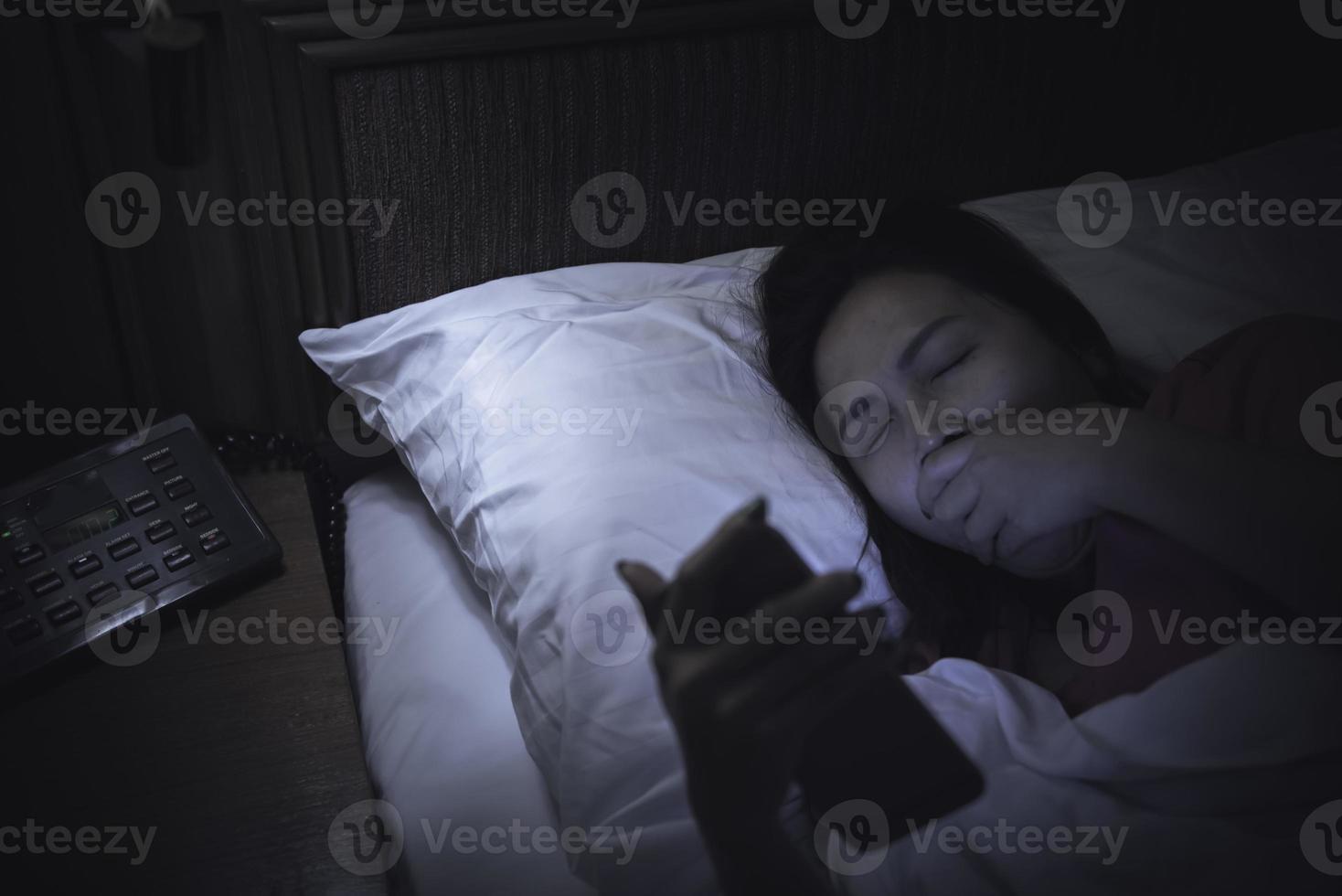 femme asiatique jouant au jeu sur smartphone dans le lit la nuit, thaïlande, toxicomane médias sociaux photo