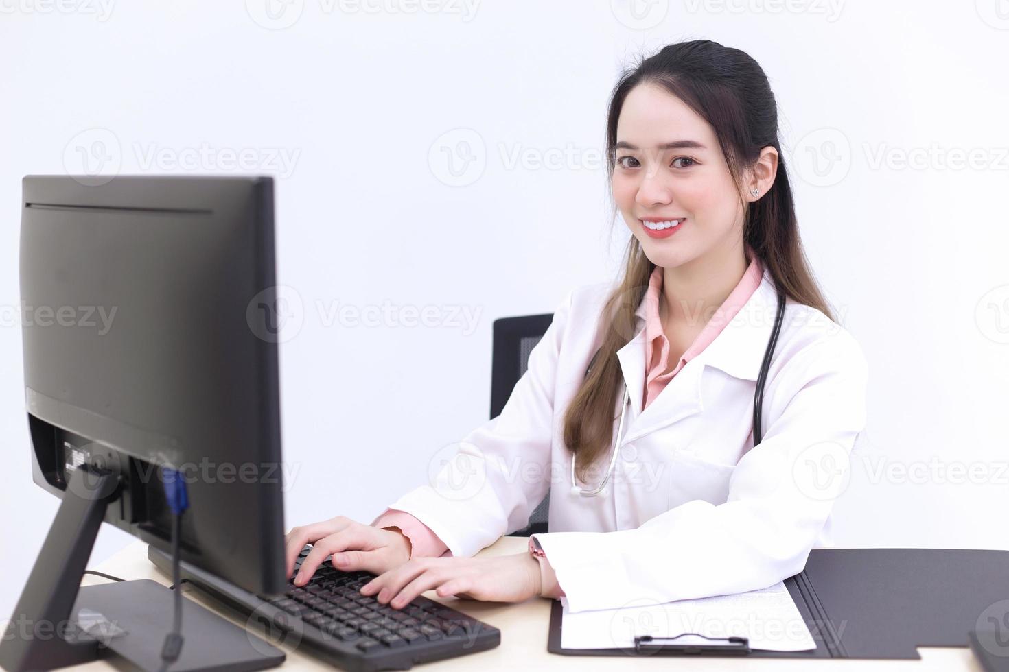 une femme médecin asiatique tape sur le clavier pour enregistrer des informations sur l'ordinateur pendant qu'elle porte un masque médical à l'hôpital. photo