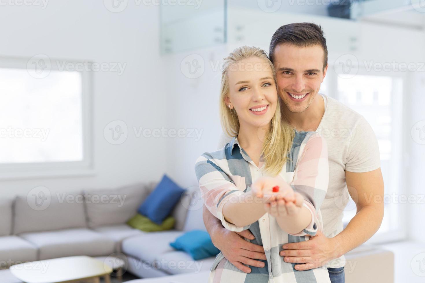 couple montrant une petite maison rouge dans les mains photo