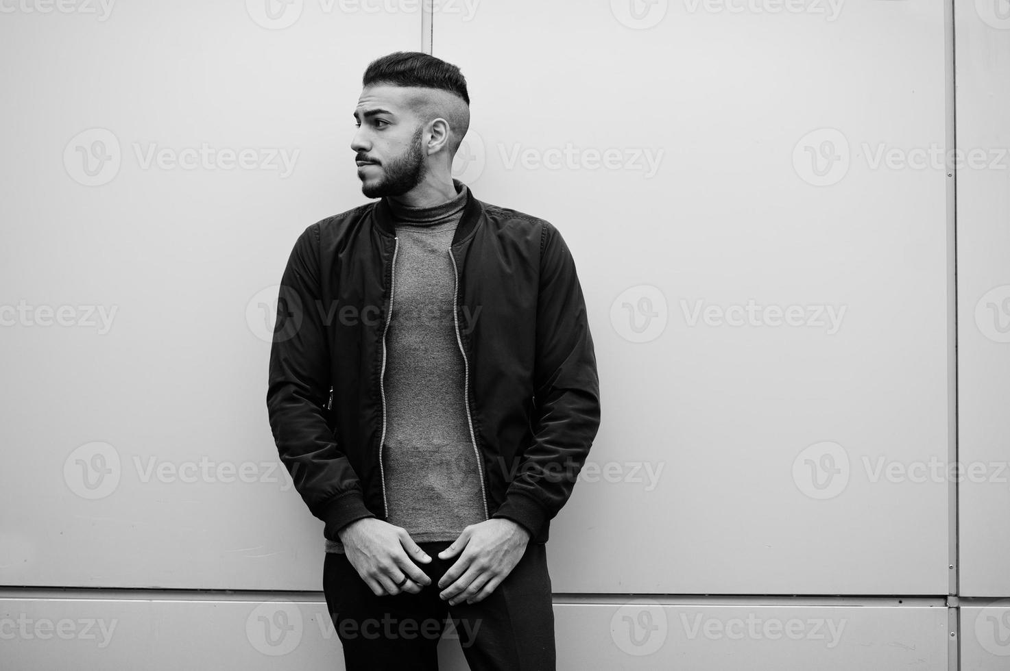 portrait d'un homme à la barbe arabe élégant portant un col roulé gris et un jaket noir. Guy modèle arabe contre le mur en acier. photo