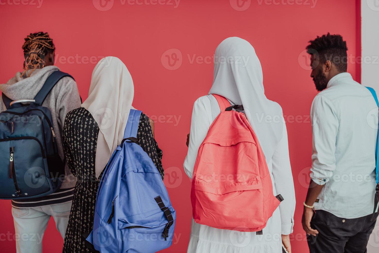 un groupe d'étudiants musulmans africains avec des sacs à dos posant sur fond rose. le concept d'éducation scolaire. photo