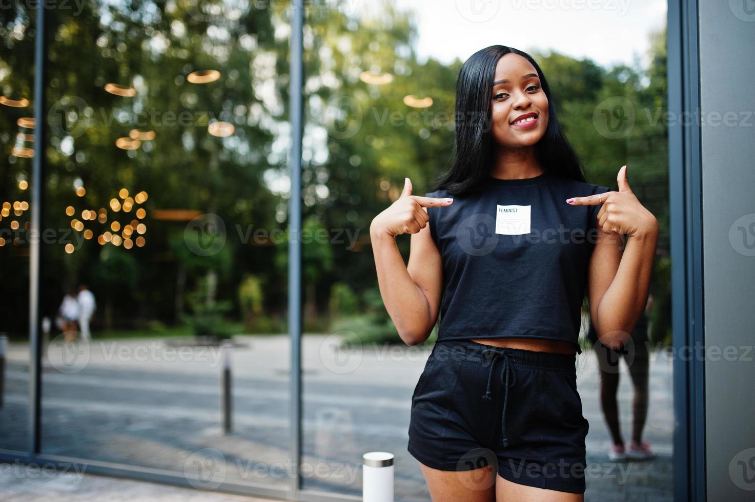 vêtements de femme afro-américaine féministe à la mode en t-shirt et short noirs, posés à l'extérieur. photo