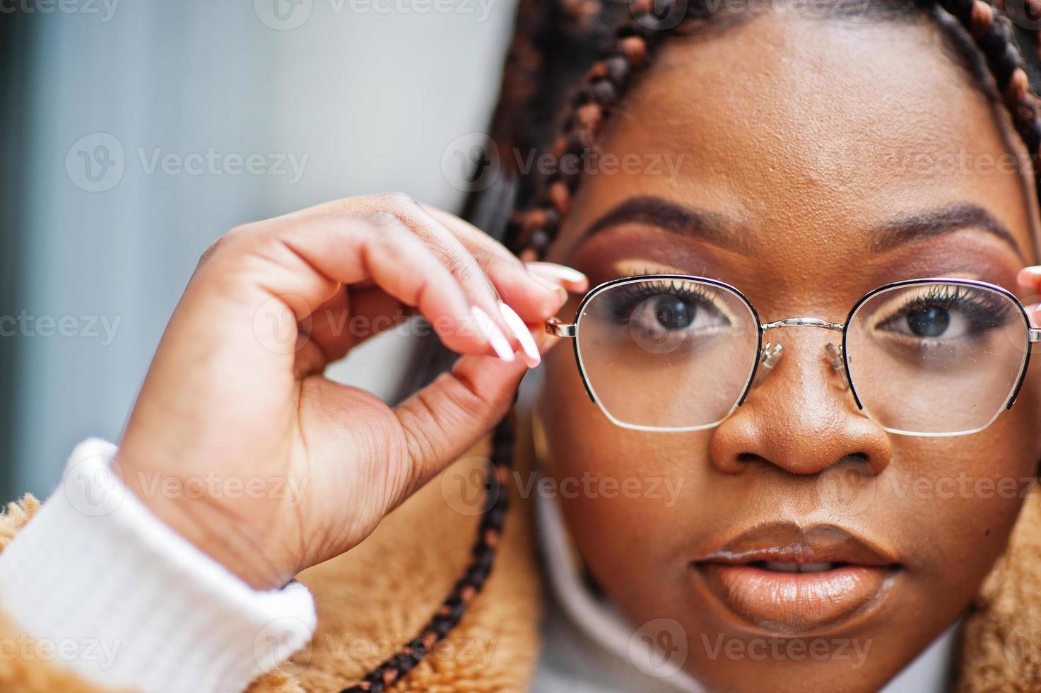 femme afro-américaine glamour en manteau de fourrure chaud, pose de lunettes dans la rue. photo