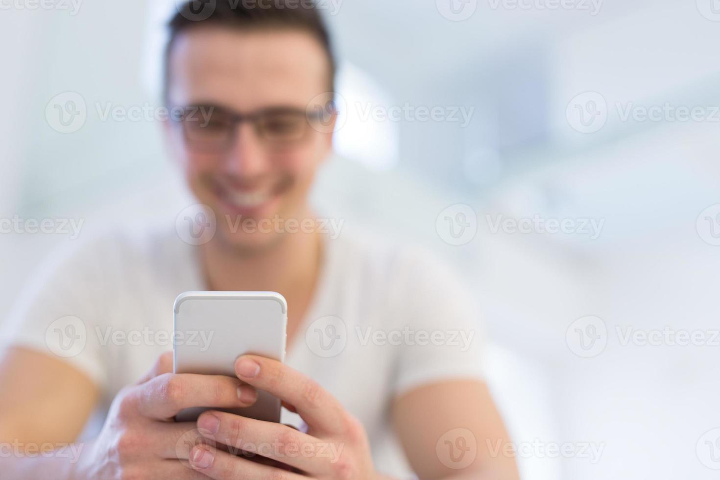 jeune homme utilisant un téléphone portable à la maison photo