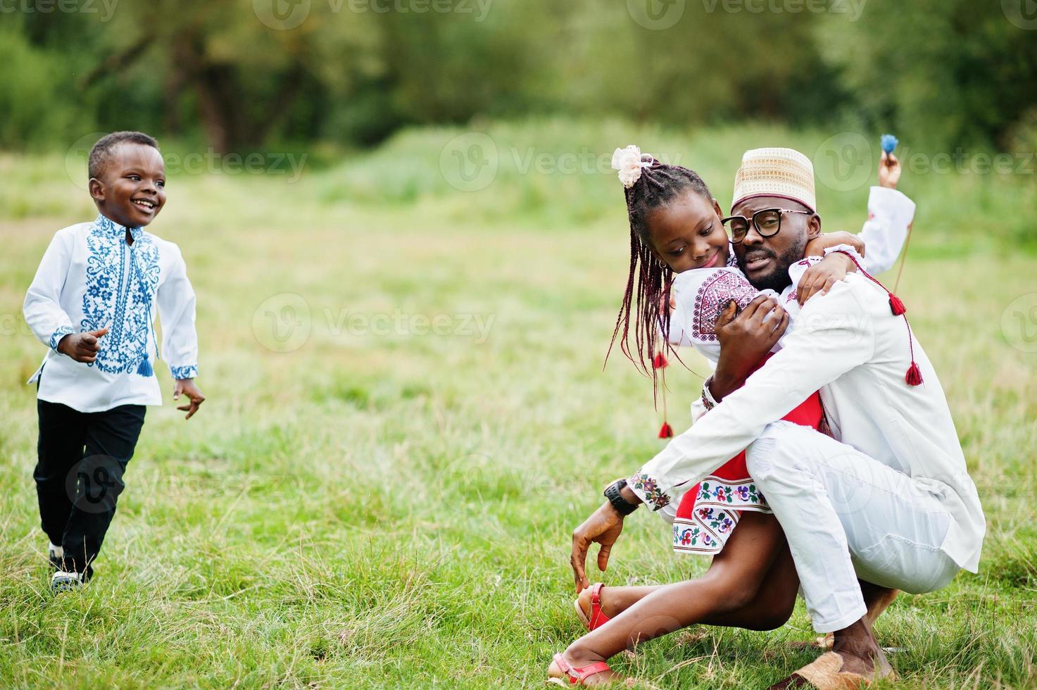 père africain avec des enfants en vêtements traditionnels au parc. photo