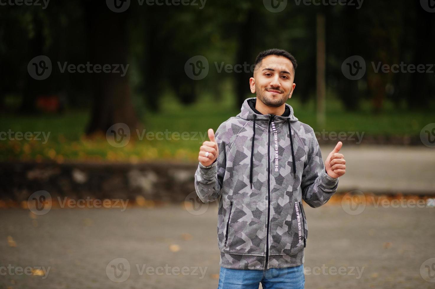 un étudiant koweïtien porte un sweat à capuche, montre le pouce en l'air. photo