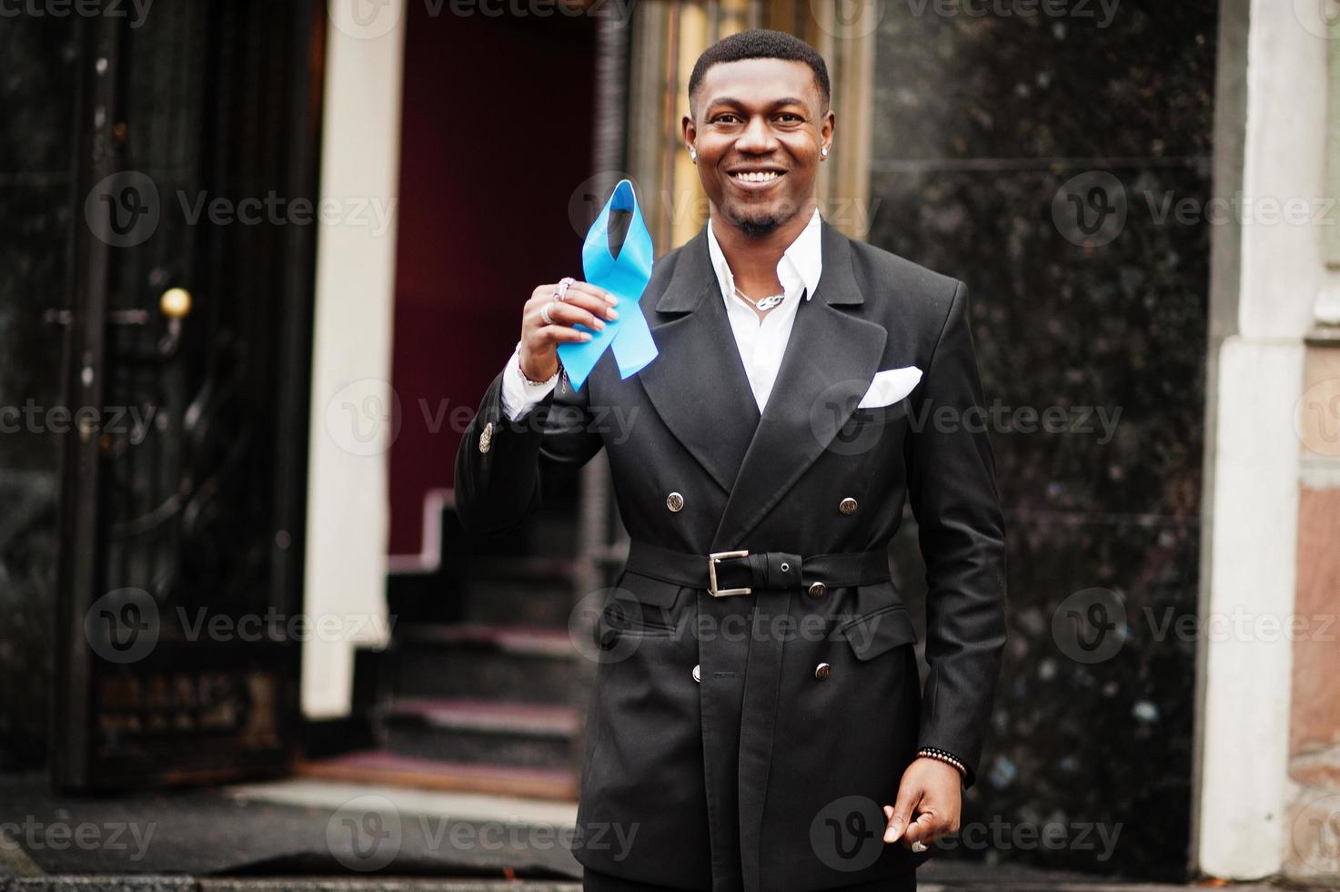 un homme afro-américain tient un ruban bleu de la prostate. sensibilisation au cancer de la santé des hommes. photo