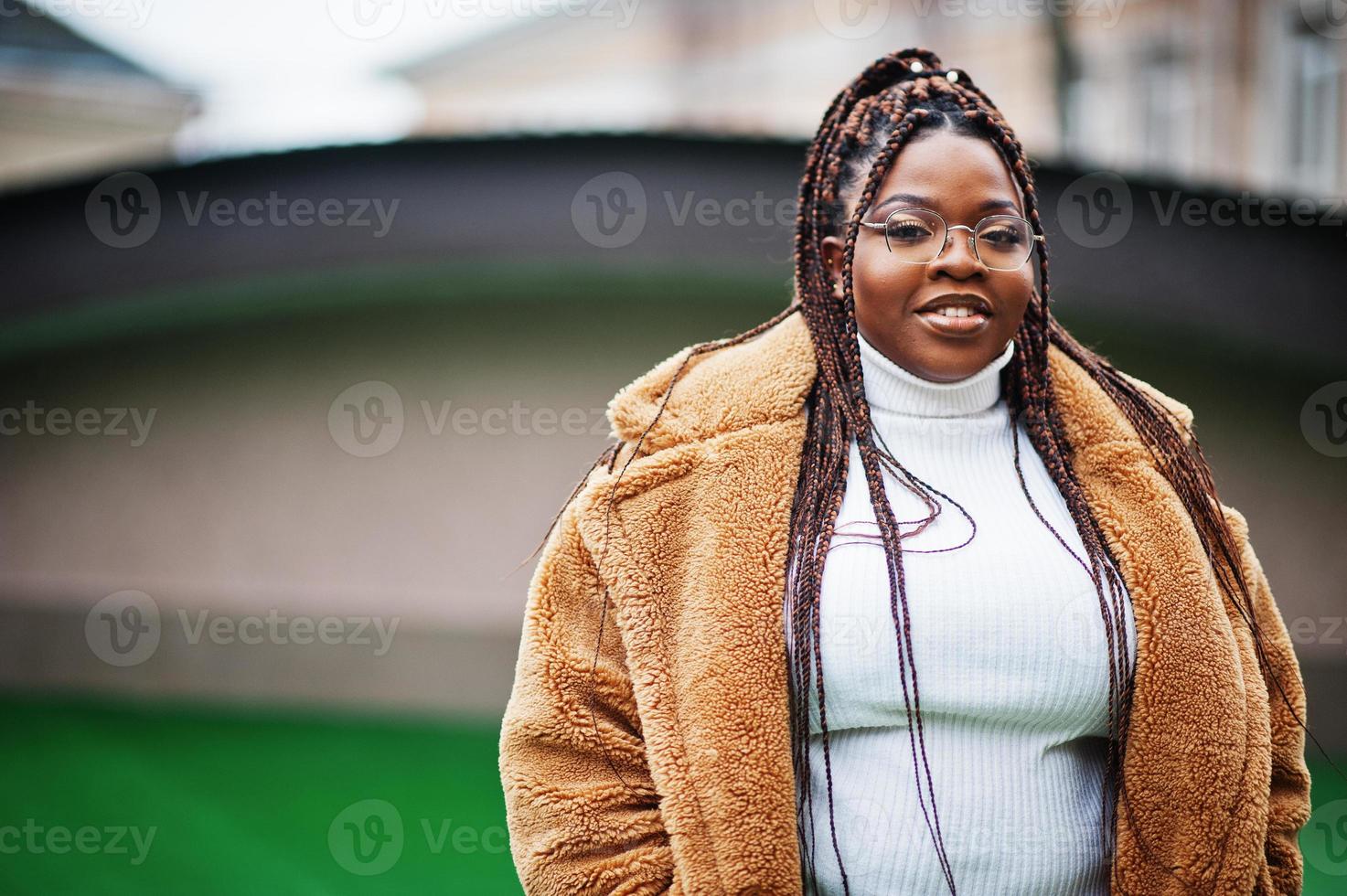 femme afro-américaine glamour en manteau de fourrure chaud pose dans la rue. photo