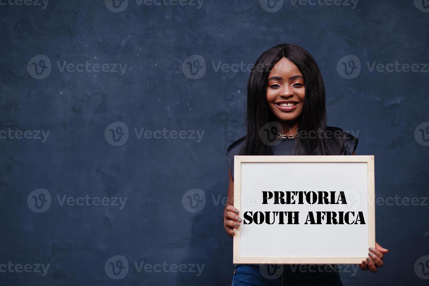 une femme africaine tient un tableau blanc avec inscription pretoria afrique du sud. concept de ville la plus peuplée d'afrique. photo