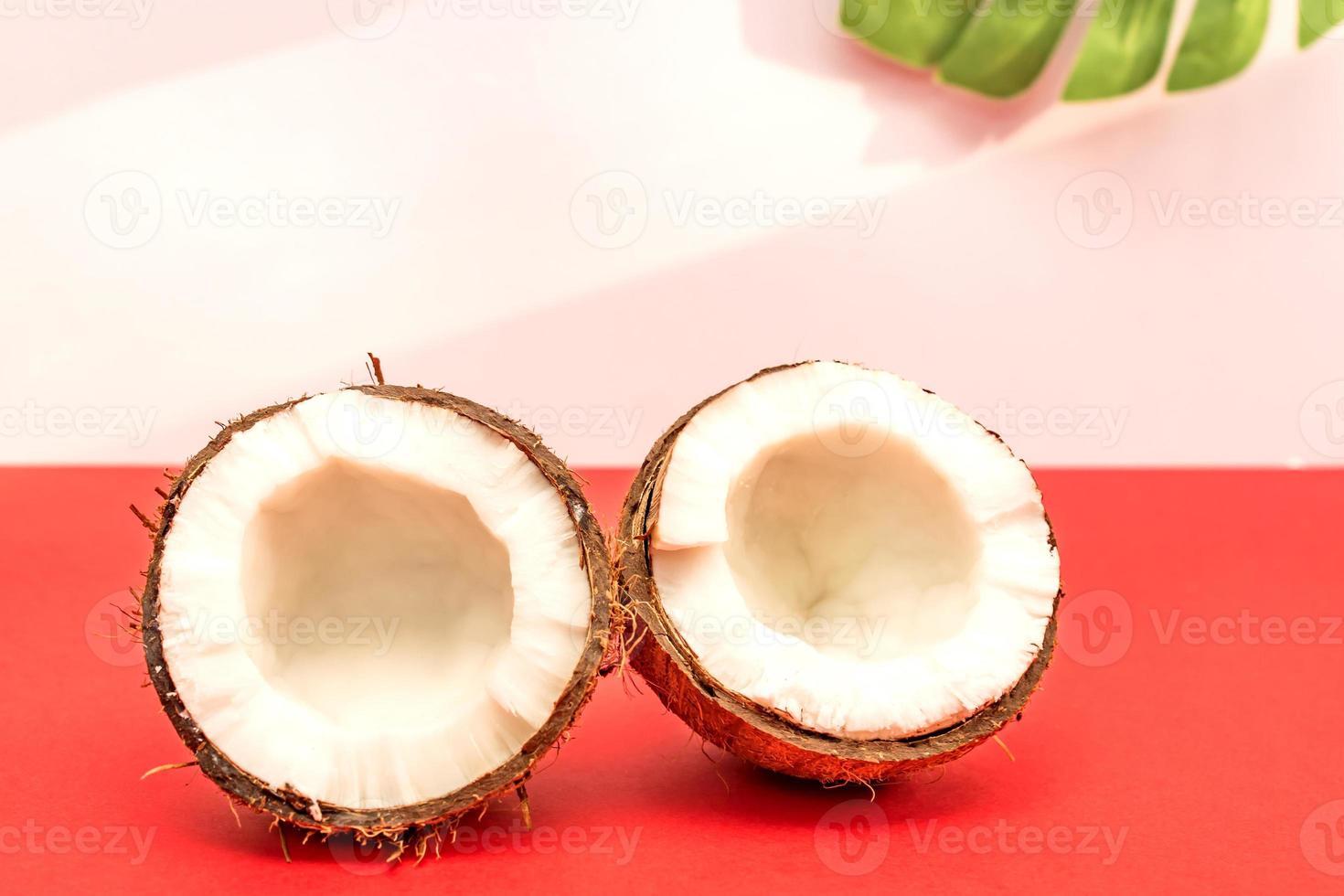 deux moitiés de noix de coco crue fraîche sur fond rouge avec des ombres claires en blanc. photo