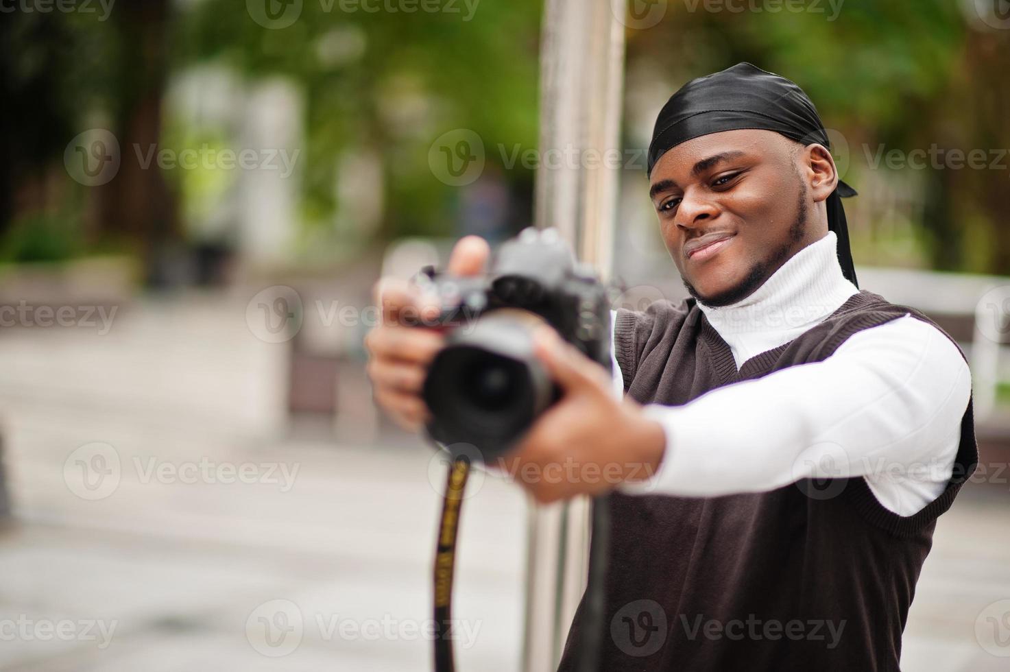 jeune vidéaste afro-américain professionnel tenant une caméra professionnelle avec un équipement professionnel. caméraman afro portant du duraq noir faisant des vidéos. photo