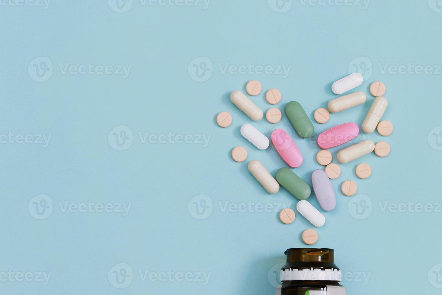 flacon de pilules qui déborde. pilules colorées sur des comprimés de surface sur un fond bleu de table. vue de dessus. concept de soins médicaux de drogue photo