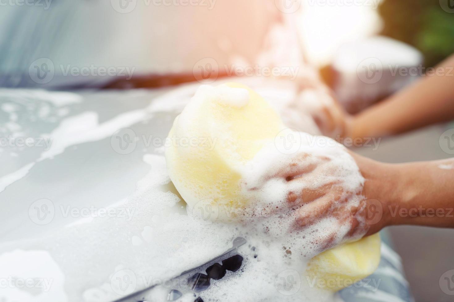 personnes travailleur homme tenant la main éponge jaune et fenêtre nettoyante en mousse à bulles pour laver la voiture. concept de lavage de voiture propre. laisser de la place pour écrire des messages. photo