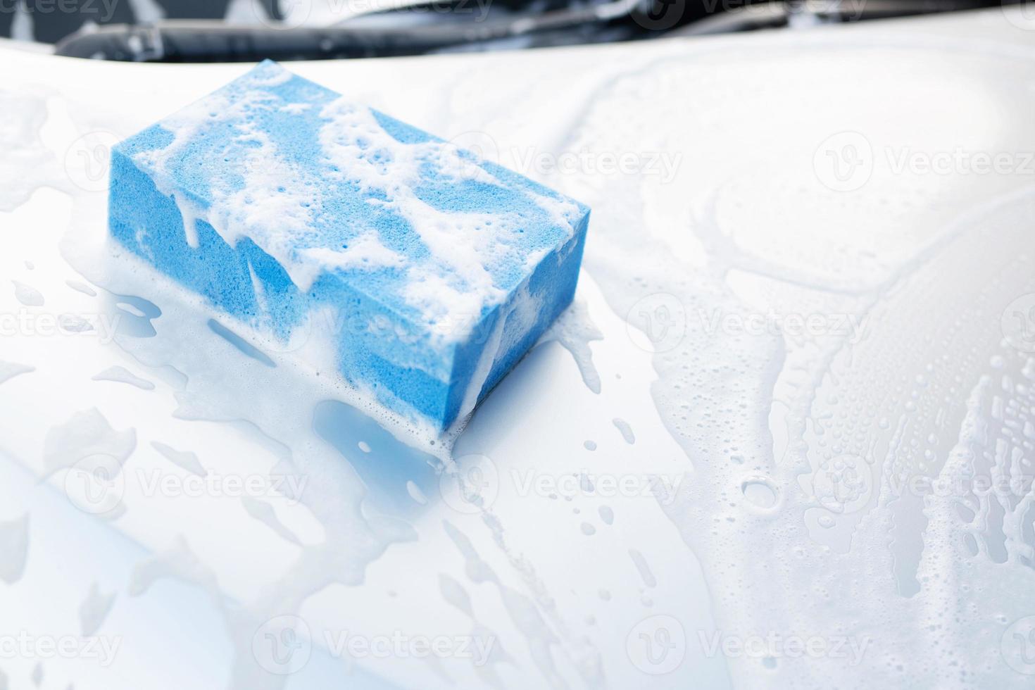 éponge bleue et fenêtre nettoyante en mousse à bulles pour laver la voiture. concept de lavage de voiture propre. laisser de la place pour écrire des messages. photo