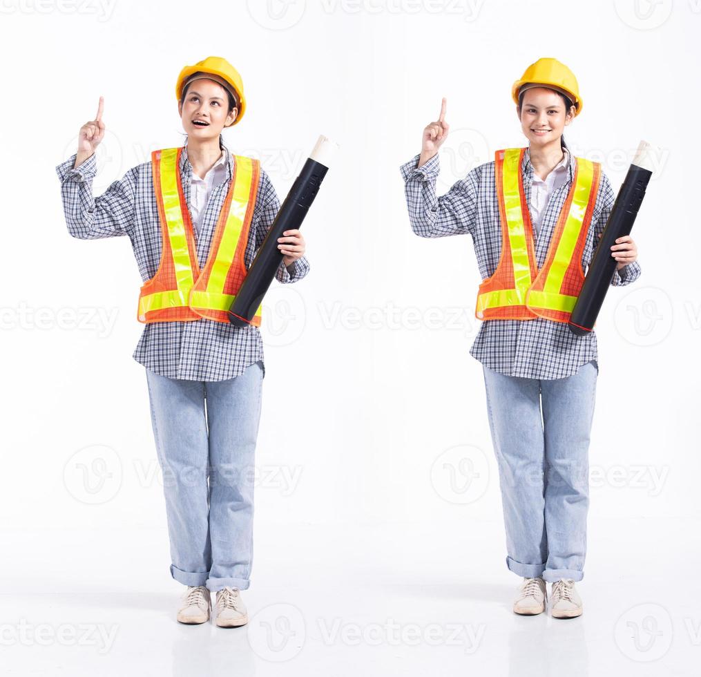 pleine longueur 20s jeune femme entrepreneur ingénieur de course mixte, pointant le doigt dans l'air vide, porter des gants de casque de sécurité vastes. femme de bureau se sent sourire heureux sur fond blanc isolé photo