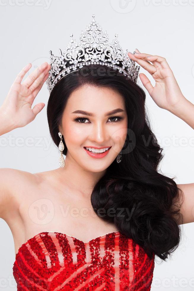 portrait du concours miss pageant en robe de bal de soirée à sequins rouges asiatiques avec ceinture en couronne de diamants argentés, maquillage de mode style de cheveux de visage, éclairage de studio fond blanc espace de copie isolé photo