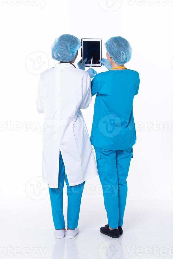 médecin professionnel de pleine longueur debout dans l'uniforme de l'hôpital discuter de l'état du dossier du patient sur la tablette. femme praticienne porter un manteau confiant en clinique, fond blanc isolé photo