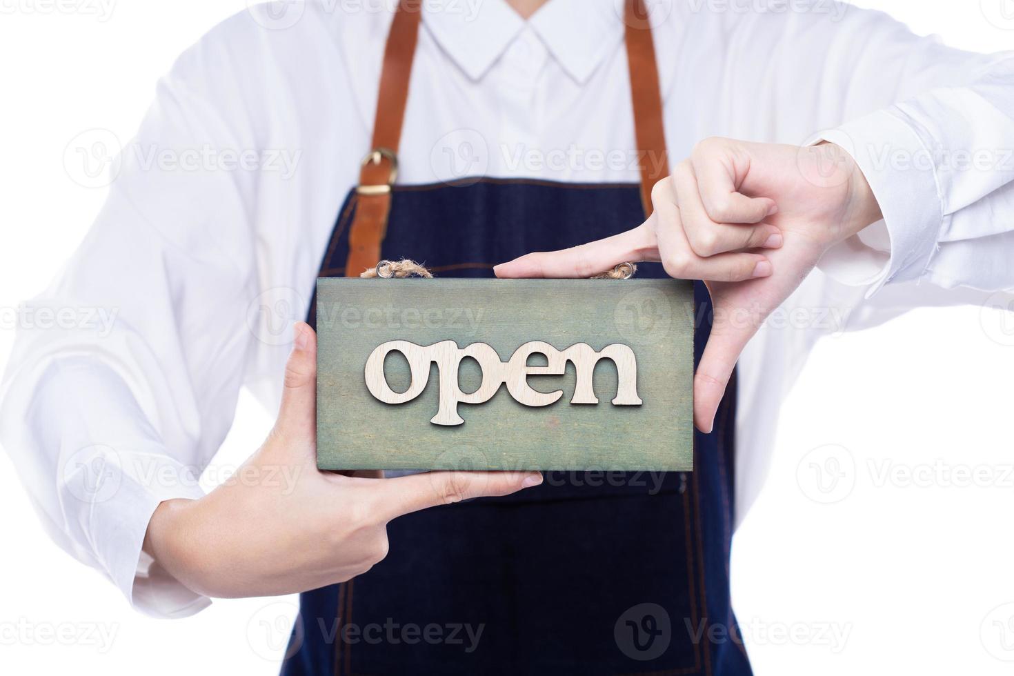 le propriétaire tient une enseigne ouverte pour montrer le service à l'entrée du magasin, du café, de la vente au détail et de la boutique d'accueil. femme entrepreneur heureuse porter une robe de serveuse comme concept de temps d'affaires ouvert à nouveau photo