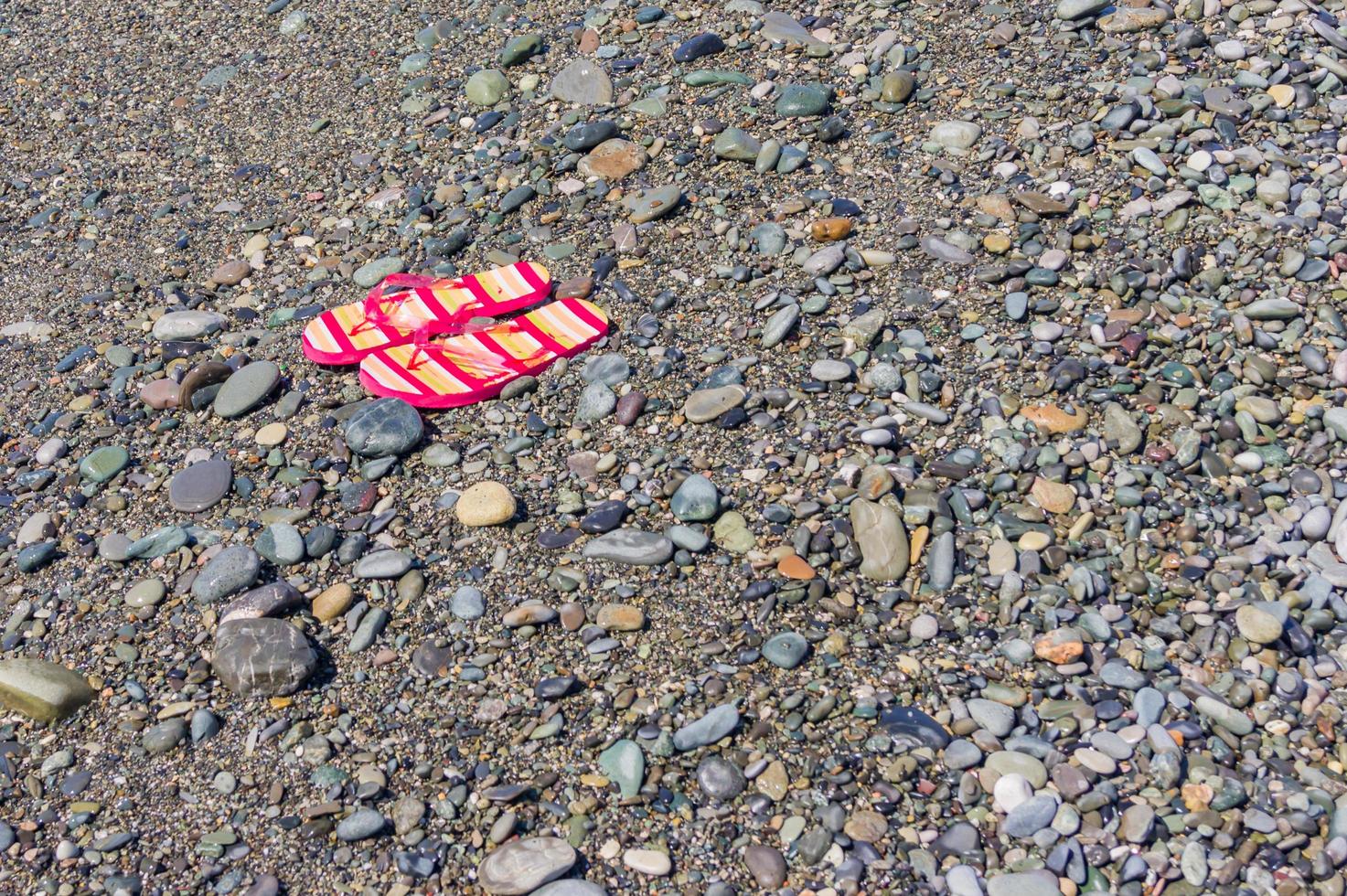 tongs pour femme sur la plage de galets. espace de copie. concept de tourisme et de vacances photo