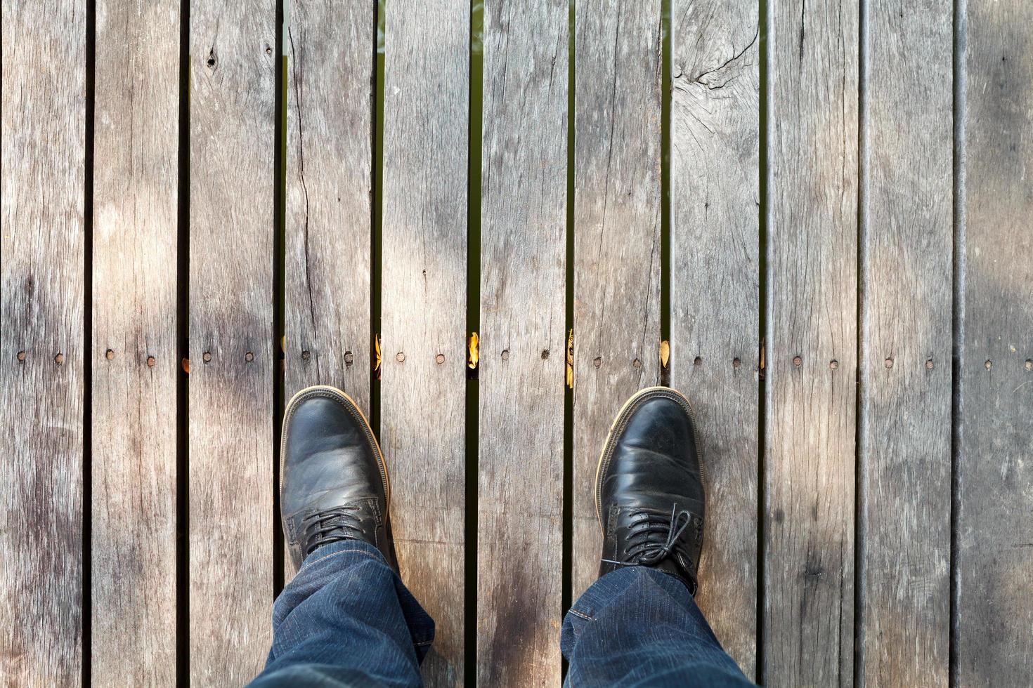 Deux jambes portant des mocassins et des jeans en denim sur fond de bois photo