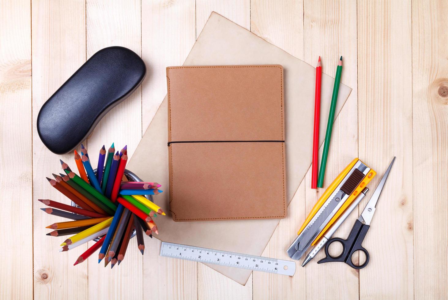 lieu de travail avec crayons de couleur et fournitures, cahier, lunettes sur table en bois photo