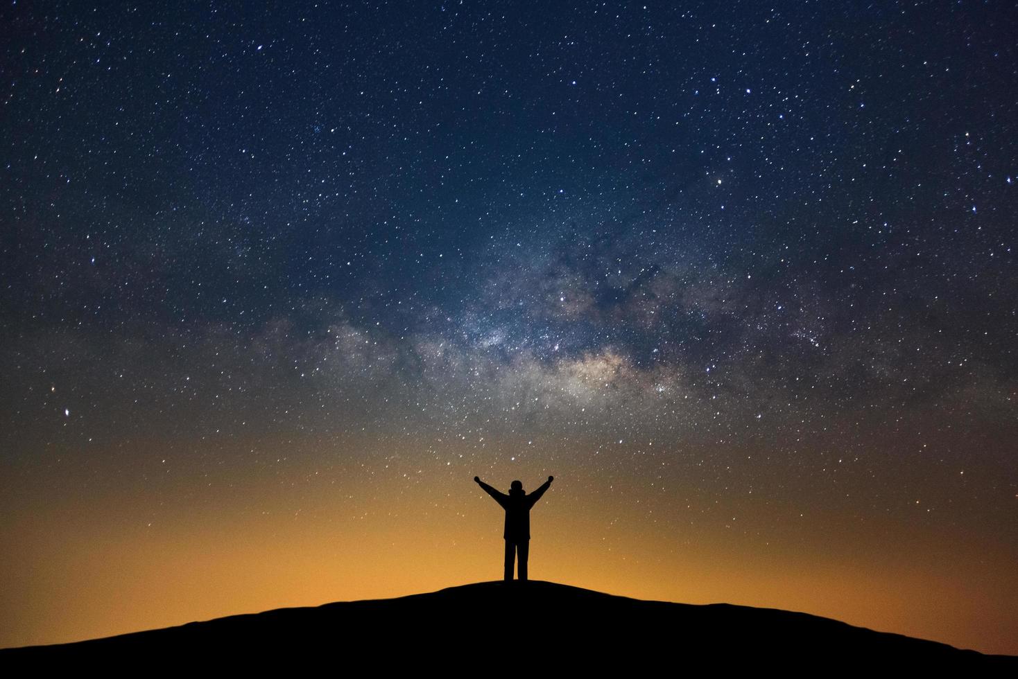 galaxie de la voie lactée avec étoiles et silhouette d'un homme heureux debout, photographie longue exposition, avec grain. photo