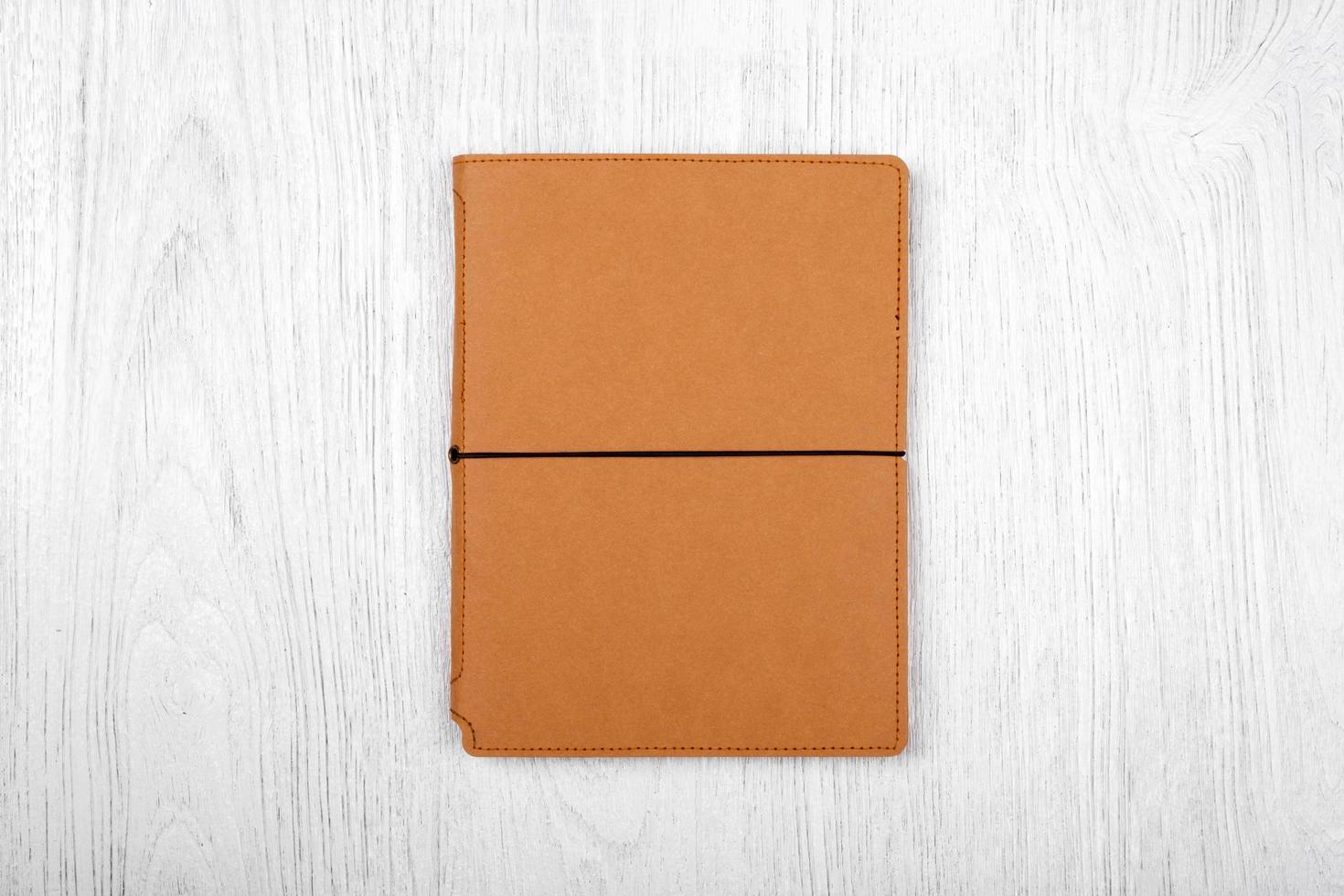 cahier marron sur table en bois blanc, vue de dessus photo