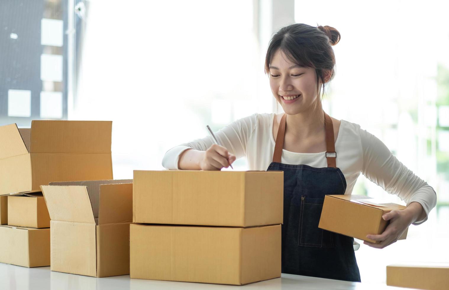 portrait d'une jeune femme asiatique sme travaillant avec une boîte à la maison le lieu de travail. propriétaire de petite entreprise de démarrage, entrepreneur de petite entreprise sme ou entreprise indépendante en ligne et concept de livraison. photo