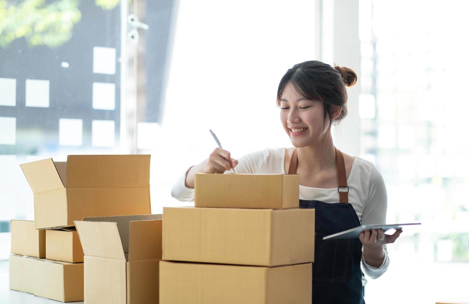 portrait d'une jeune femme asiatique sme travaillant avec une boîte à la maison le lieu de travail. propriétaire de petite entreprise de démarrage, entrepreneur de petite entreprise sme ou entreprise indépendante en ligne et concept de livraison. photo